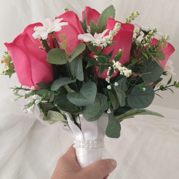 Bouquet de rosas rosas com folhagem e detalhes brancos em vaso decorado.