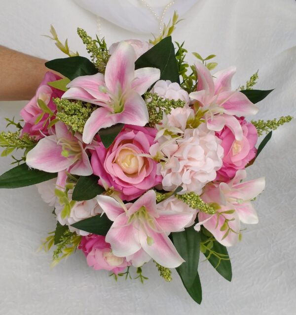 Bouquet de flores rosa e branca com dálias, lírios e folhagens verdes vibrantes.