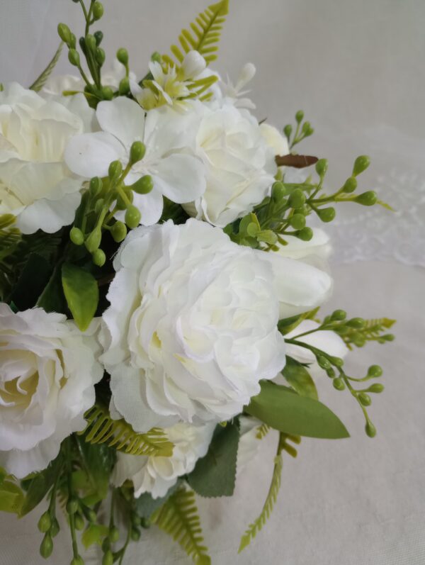 Bouquet de flores brancas com folhagem verde e detalhes decorativos.