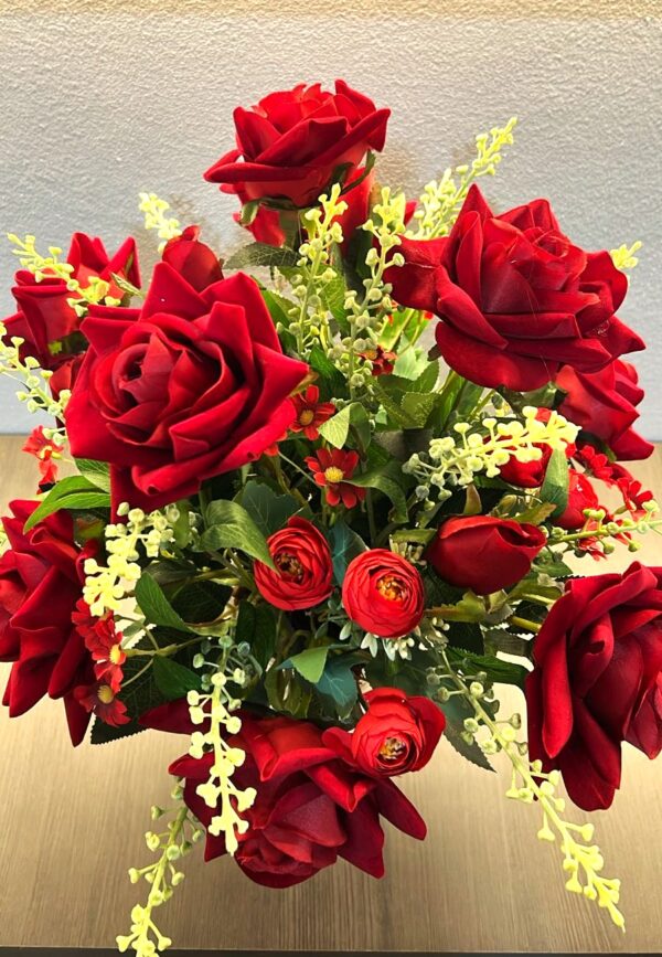 Rosas vermelhas em arranjo floral com folhagens e detalhes amarelos.