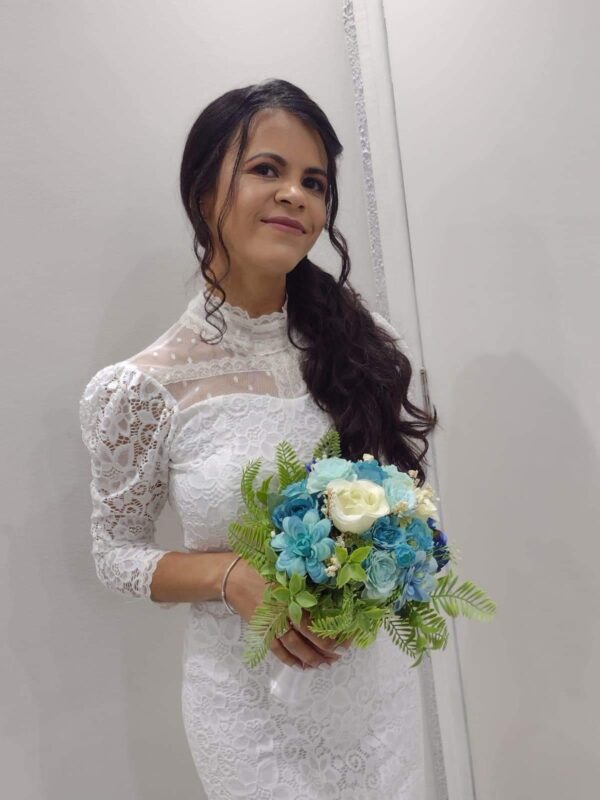 Buquê de noiva com flores azuis e brancas, decorado com folhagem verdejante.