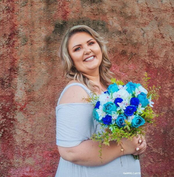 Buquê de flores azul com rosas e orquídeas, mulher sorridente segurando o bouquet.