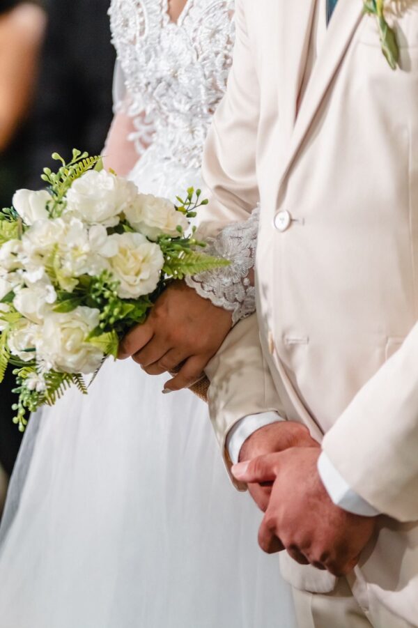 Buquê de flores brancas nas mãos de um casal em casamento.