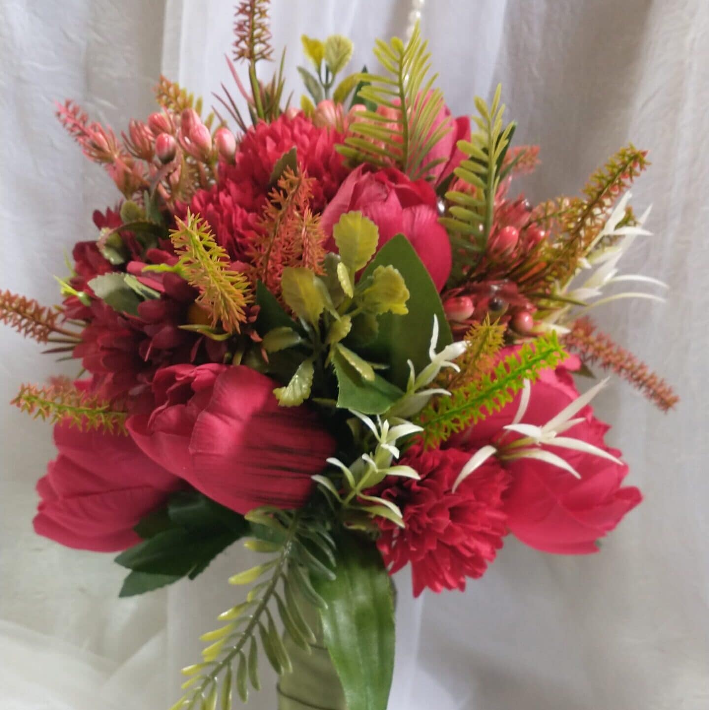 Buquê de flores colorido com rosas, folhagem e detalhes delicados.