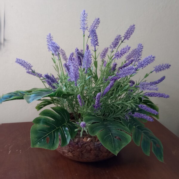 Lavanda artificial em vaso decorativo com folhas verdes vibrantes.