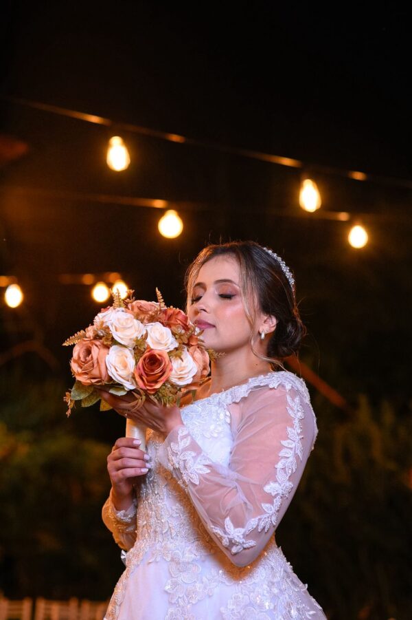 Florista segurando buquê de flores em ambiente com iluminação quente.