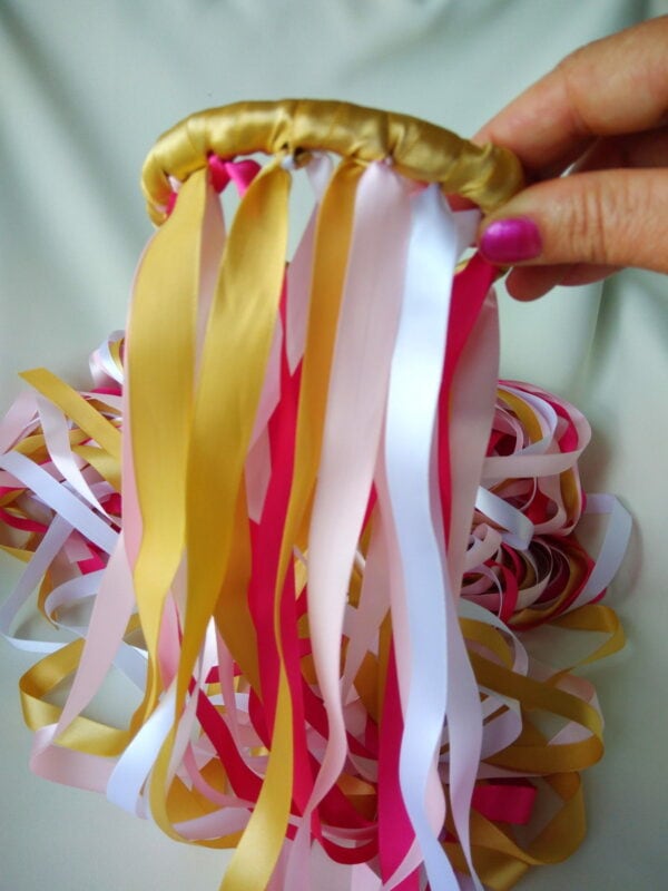 Cordão de fita decorativa com laços coloridos, usado em artesanato e decoração de festas.