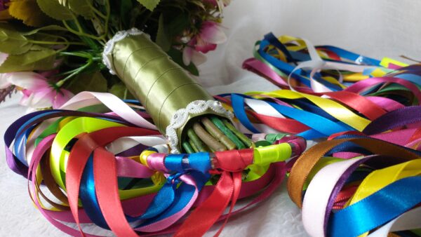 Buquê com fitas coloridas e flores artificiais para casamento ou ocasião especial.