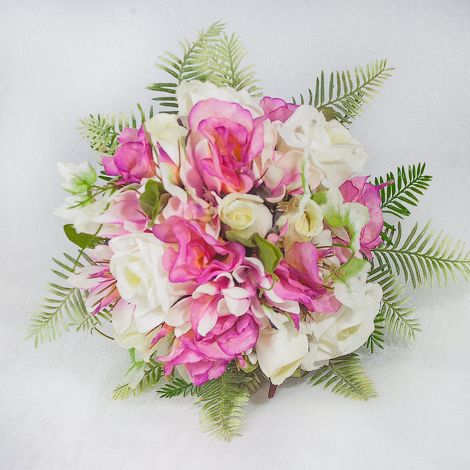 Bouquet com flores brancas e rosa, decorado com folhagem verde, ideal para casamentos.