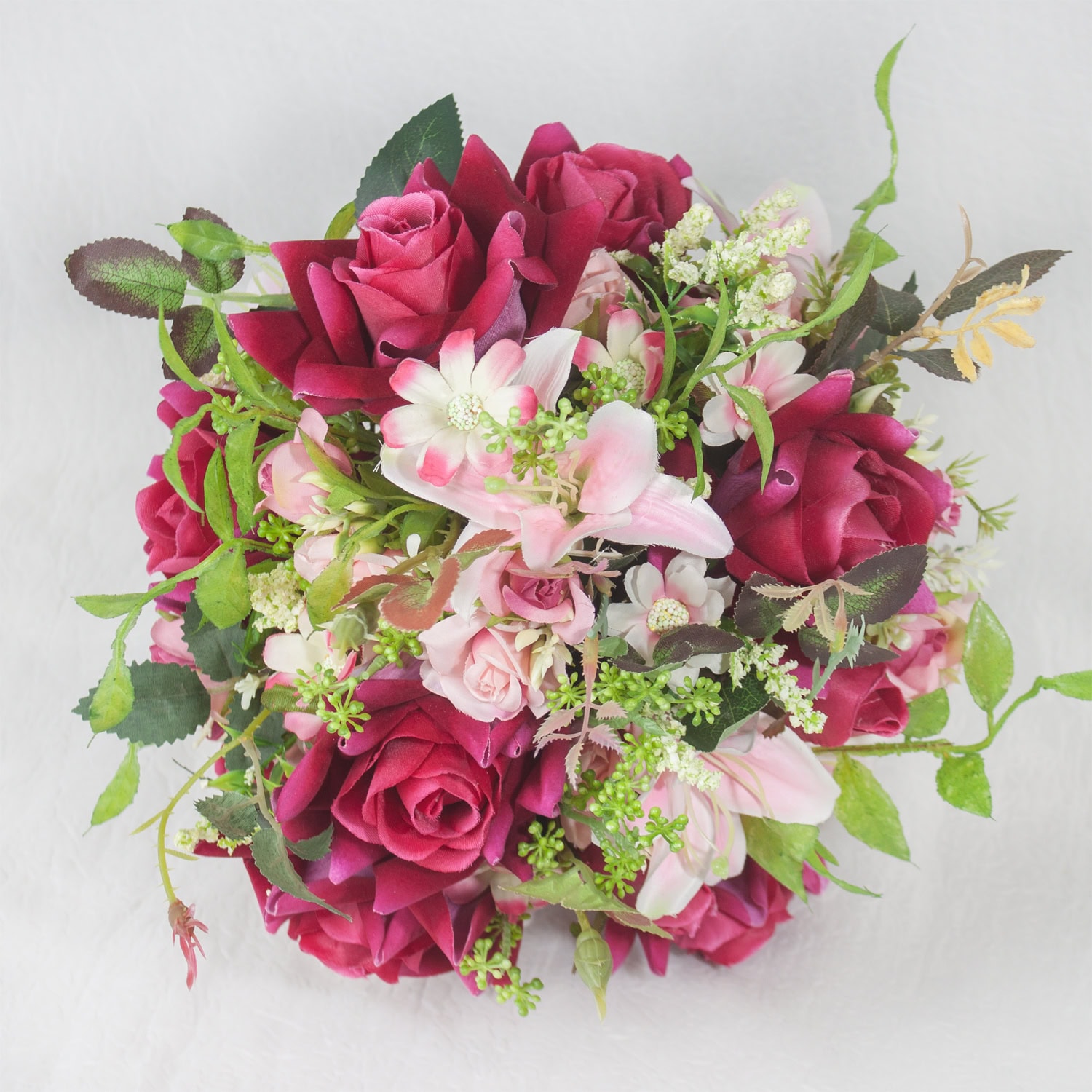 Ramo de flores com rosas, peônias e folhagens em tons de rosa e vermelho.