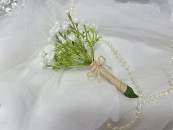 Buquê de flores brancas com fita de rafia e pérola, em fundo de tule branco.